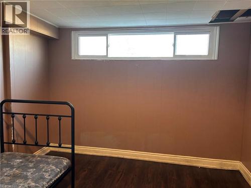 Unfurnished bedroom featuring dark wood-style floors and multiple windows - 1224 Dunsmure Road, Hamilton, ON - Indoor Photo Showing Other Room