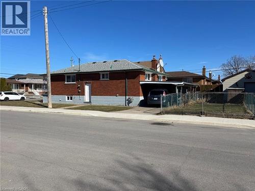 View of front of property with brick siding, driveway, and a carport - 1224 Dunsmure Road, Hamilton, ON - Outdoor