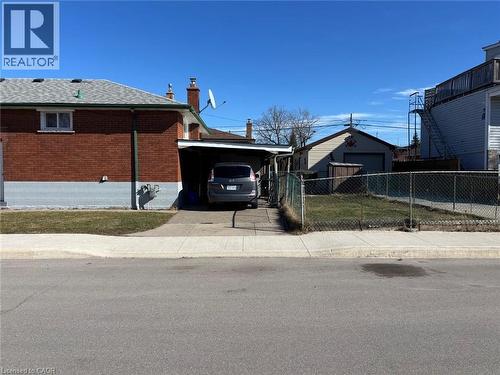 View of side of home with a carport, brick siding, an outdoor structure, a chimney, and concrete driveway - 1224 Dunsmure Road, Hamilton, ON - Outdoor