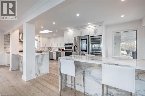 Kitchen with light stone counters, a kitchen breakfast bar, wine cooler, white cabinetry, and recessed lighting - 624 North Shore Boulevard E, Burlington, ON - Indoor Photo Showing Kitchen With Stainless Steel Kitchen With Upgraded Kitchen