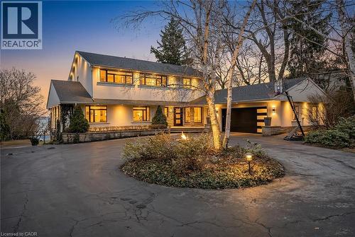 View of front facade with curved driveway, a garage, and stucco siding - 624 North Shore Boulevard E, Burlington, ON - Outdoor With Deck Patio Veranda