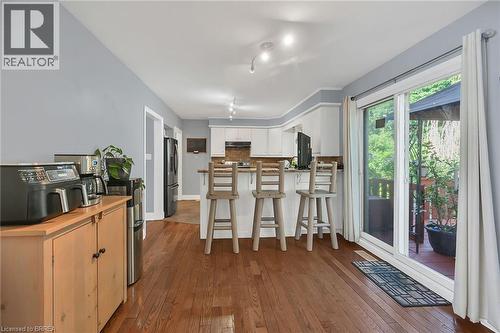 Kitchen with dark wood finished floors, a breakfast bar area, a peninsula, freestanding refrigerator, and white cabinets - 56 Forsythe Avenue, Brantford, ON - Indoor