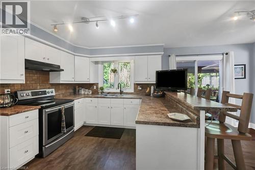 Kitchen featuring dark countertops, electric stove, a breakfast bar, white cabinets, and track lighting - 56 Forsythe Avenue, Brantford, ON - Indoor Photo Showing Kitchen With Double Sink