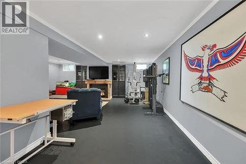 Exercise room featuring a warm lit fireplace, ornamental molding, recessed lighting, and finished concrete flooring - 56 Forsythe Avenue, Brantford, ON - Indoor