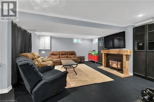 Living area with a glass covered fireplace and finished concrete flooring - 56 Forsythe Avenue, Brantford, ON - Indoor Photo Showing Living Room With Fireplace