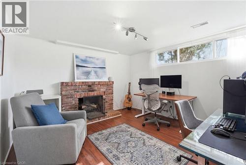 Office featuring a brick fireplace, wood finished floors, and track lighting - 227 Walden Drive, Burlington, ON - Indoor Photo Showing Other Room With Fireplace