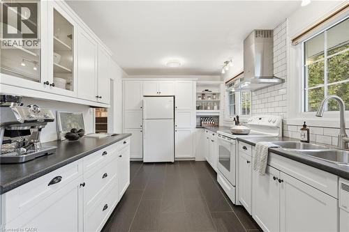 Kitchen with dark countertops, white appliances, island exhaust hood, and glass fronted cabinets - 227 Walden Drive, Burlington, ON - Indoor Photo Showing Kitchen With Double Sink