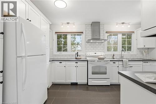 Kitchen with white appliances, white cabinets, dark countertops, and decorative backsplash - 227 Walden Drive, Burlington, ON - Indoor Photo Showing Kitchen