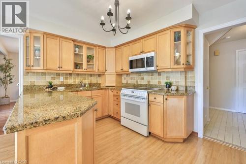 Kitchen featuring glass fronted cabinets, light wood finish cabinets, white range with electric stovetop, and light stone counters - 700 Fieldstone Road, Mississauga, ON - Indoor Photo Showing Kitchen