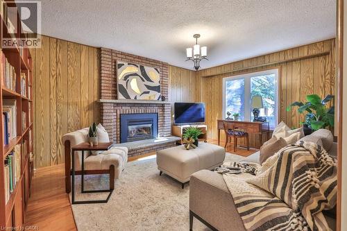 Living room with a fireplace, wood finished floors, wood walls, and a textured ceiling - 700 Fieldstone Road, Mississauga, ON - Indoor Photo Showing Living Room With Fireplace