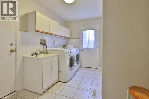 Laundry area with independent washer and dryer, light tile patterned floors, and cabinet space - 700 Fieldstone Road, Mississauga, ON - Indoor Photo Showing Laundry Room