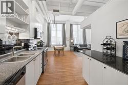 Kitchen featuring stainless steel appliances, white cabinetry, light wood finished floors, and open shelves - 