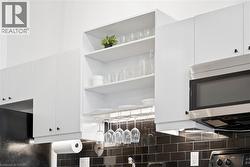Kitchen view of stainless steel microwave, white cabinets, and open shelves - 