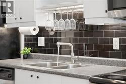 Kitchen with white cabinets, backsplash, dishwasher, and light countertops - 