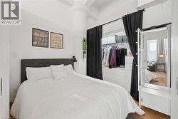 Bedroom with wood finished floors, multiple windows, a high ceiling, and a closet - 
