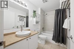 Bathroom featuring vanity, shower / tub combo with curtain, and light tile patterned floors - 