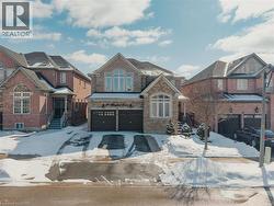 View of front of home with an attached garage, concrete driveway, stone siding, and brick siding - 