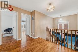 Hall featuring an upstairs landing, hanging lights, and wood finished floors - 