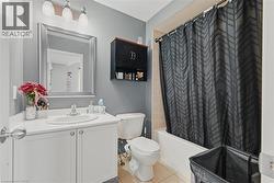 Full bath featuring vanity, shower / bath combo, and light tile patterned floors - 