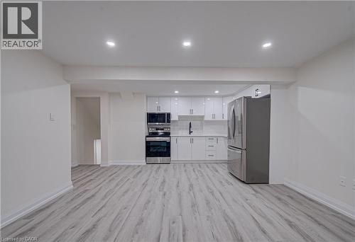 Kitchen featuring light countertops, stainless steel appliances, recessed lighting, white cabinets, and light wood finished floors - 383 Rexford Drive Unit# 2, Hamilton, ON - Indoor