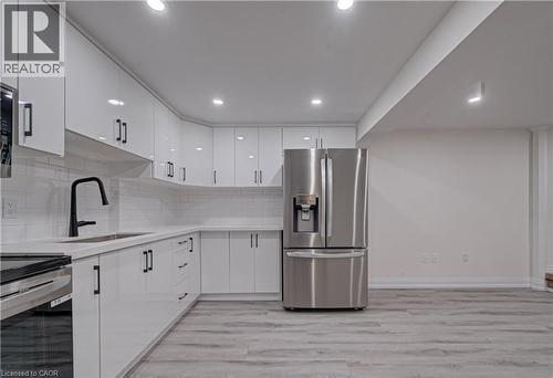Kitchen with stainless steel appliances, light wood-style floors, white cabinetry, recessed lighting, and decorative backsplash - 383 Rexford Drive Unit# 2, Hamilton, ON - Indoor Photo Showing Kitchen With Upgraded Kitchen