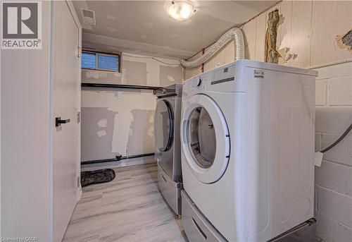 Laundry area featuring separate washer and dryer, concrete block wall, and light wood-style floors - 383 Rexford Drive Unit# 2, Hamilton, ON - Indoor Photo Showing Laundry Room