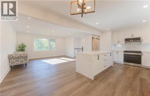 Kitchen with open floor plan, tasteful backsplash, stainless steel electric range oven, white cabinetry, and a barn door - 90 Culpepper Drive, Waterloo, ON - Indoor Photo Showing Kitchen