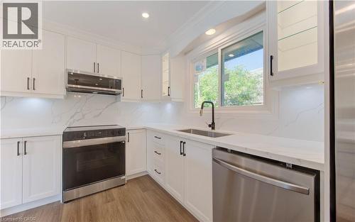 Kitchen with stainless steel appliances, backsplash, ornamental molding, white cabinets, and light wood-style flooring - 90 Culpepper Drive, Waterloo, ON - Indoor Photo Showing Kitchen With Upgraded Kitchen