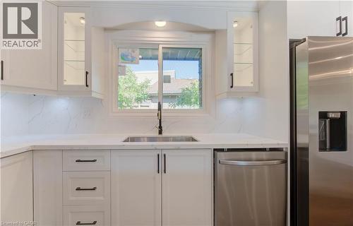 Kitchen with white cabinets, stainless steel appliances, glass insert cabinets, and light stone counters - 90 Culpepper Drive, Waterloo, ON - Indoor Photo Showing Kitchen