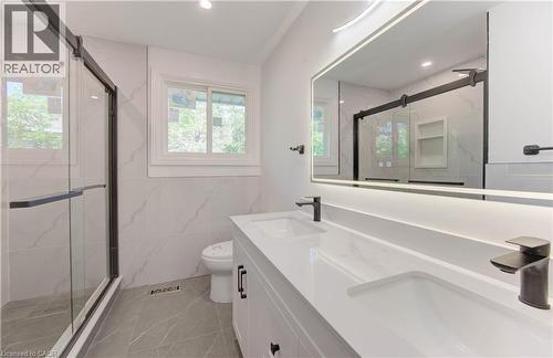 Full bath featuring double vanity, a marble finish shower, recessed lighting, and tile walls - 90 Culpepper Drive, Waterloo, ON - Indoor Photo Showing Bathroom