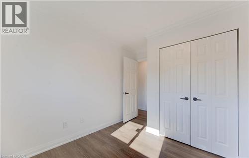 Unfurnished bedroom featuring wood finished floors, crown molding, and a closet - 90 Culpepper Drive, Waterloo, ON - Indoor Photo Showing Other Room