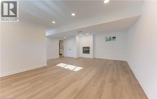 Finished below grade area featuring recessed lighting, light wood-style flooring, and a glass covered fireplace - 90 Culpepper Drive, Waterloo, ON - Indoor Photo Showing Other Room