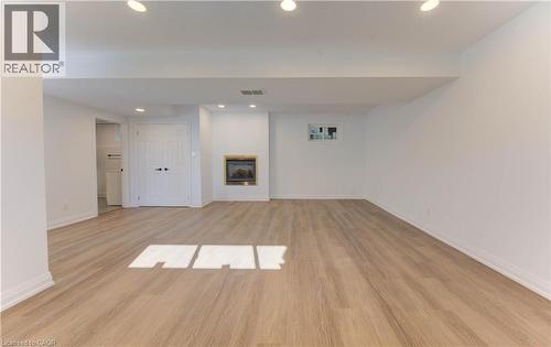 Finished basement featuring recessed lighting, a glass covered fireplace, and light wood finished floors - 90 Culpepper Drive, Waterloo, ON - Indoor Photo Showing Other Room
