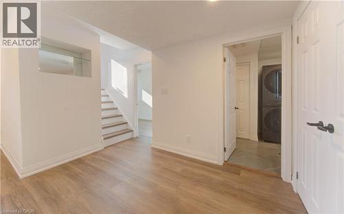 Spare room featuring light wood-style flooring, stacked washer and clothes dryer, and stairway - 90 Culpepper Drive, Waterloo, ON - Indoor Photo Showing Other Room