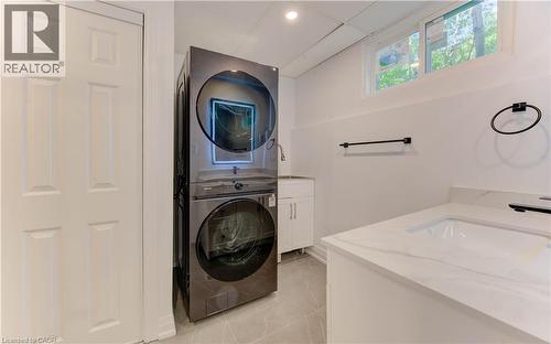 Laundry area with light tile patterned flooring, cabinet space, estacked washer and dryer, and recessed lighting - 90 Culpepper Drive, Waterloo, ON - Indoor Photo Showing Laundry Room