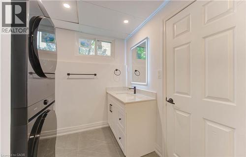 Bathroom with vanity, light tile patterned floors, stacked washer and clothes dryer, recessed lighting, and ornamental molding - 90 Culpepper Drive, Waterloo, ON - Indoor Photo Showing Laundry Room
