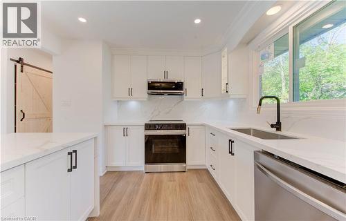 Kitchen featuring a barn door, electric stove, stainless steel dishwasher, light stone countertops, and white cabinetry - 90 Culpepper Drive, Waterloo, ON - Indoor Photo Showing Kitchen With Upgraded Kitchen