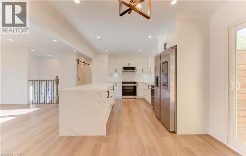 Kitchen with a barn door, white cabinets, stainless steel appliances, recessed lighting, and light wood-style flooring - 90 Culpepper Drive, Waterloo, ON - Indoor Photo Showing Kitchen