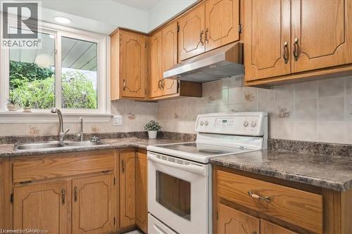 Kitchen with white electric range, dark countertops, and wood finish cabinetry - 47 Claycroft Crescent Unit# Upper, Kitchener, ON - Indoor Photo Showing Kitchen With Double Sink