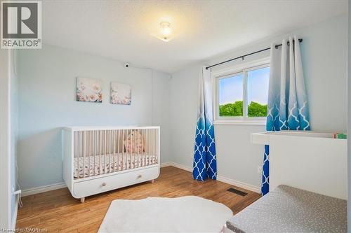Bedroom featuring light wood finished floors, a crib, and a textured ceiling - 47 Claycroft Crescent Unit# Upper, Kitchener, ON - Indoor Photo Showing Bedroom