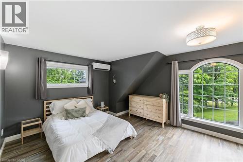 Guest house primary bedroom has large windows, closet, consistent grey laminate flooring throughout, ductless heating and air system - 515 Hamilton Drive, Ancaster, ON - Indoor Photo Showing Bedroom