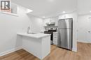 Kitchen featuring stainless steel appliances, white cabinetry, a peninsula, light wood-style flooring, and backsplash - 187 Oak Avenue Unit# Lower, Hamilton, ON  - Indoor Photo Showing Kitchen 