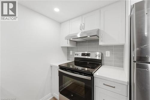 Kitchen with stainless steel appliances, white cabinets, tasteful backsplash, recessed lighting, and light stone countertops - 187 Oak Avenue Unit# Lower, Hamilton, ON - Indoor Photo Showing Kitchen