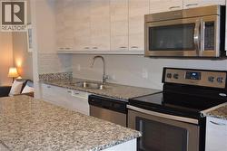 Kitchen with stainless steel appliances, light stone countertops, backsplash, and white cabinets - 