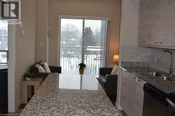 Kitchen featuring light stone countertops, tasteful backsplash, dishwasher, and white cabinetry - 