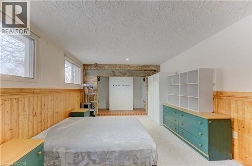 Bedroom featuring wood walls, wainscoting, light colored carpet, and a textured ceiling - 98 Shea Crescent, Kitchener, ON - Indoor