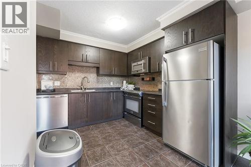 Kitchen featuring dark wood finish cabinetry, stainless steel appliances, dark countertops, a textured ceiling, and tasteful backsplash - 208 Templewood Drive, Kitchener, ON - Indoor Photo Showing Kitchen With Stainless Steel Kitchen With Upgraded Kitchen