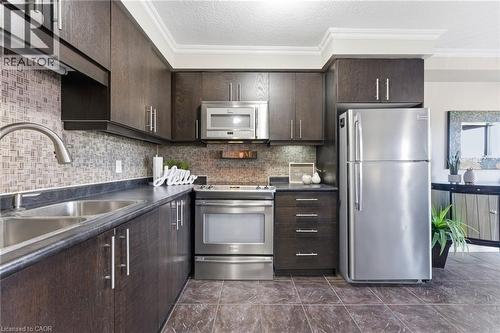 Kitchen featuring dark wood finish cabinets, dark countertops, stainless steel appliances, a textured ceiling, and ornamental molding - 208 Templewood Drive, Kitchener, ON - Indoor Photo Showing Kitchen With Stainless Steel Kitchen With Double Sink With Upgraded Kitchen
