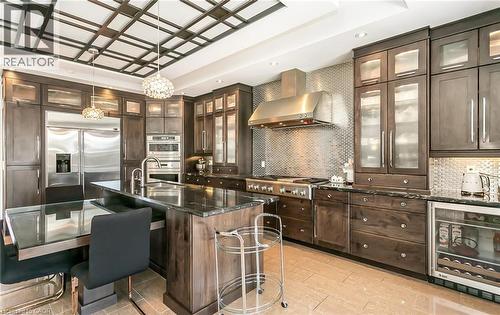 Kitchen featuring wine cooler, dark wood finish cabinetry, a kitchen breakfast bar, a kitchen island with sink, and decorative light fixtures - 24 Jacob Gingrich Drive, Kitchener, ON - Indoor Photo Showing Kitchen With Upgraded Kitchen