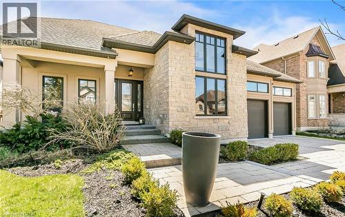 View of front of property with concrete driveway, stucco siding, roof with shingles, a garage, and stone siding - 24 Jacob Gingrich Drive, Kitchener, ON - Outdoor With Facade